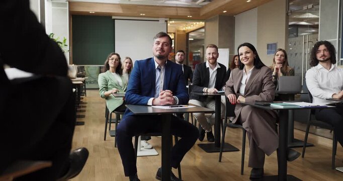 Audience listens to speaker at business seminar. Professionals in a modern classroom watch a presentation and join a collaborative meeting and workshop. Team training and leadership concept.