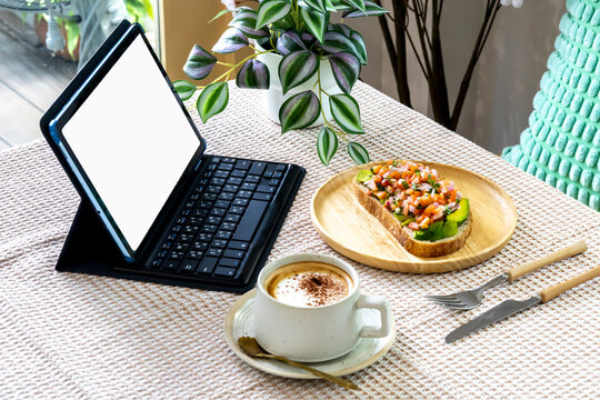 A portable digital tablet touchpad mockup with wireless keyboard on the table in cafe coffee shop.