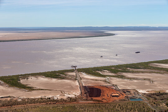 Arial view of the iron ore vessel loading jetty on the West Arm of the Cambridge gulf with 2 tug boats and a mooring pontoon moored near the jetty, Wyndam Western Australia.