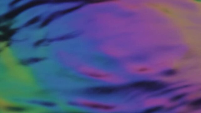 Iridescent oil slick ripples on calm water surface