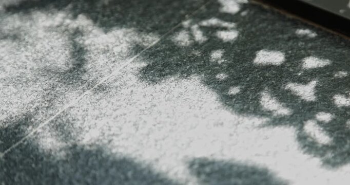 Close-up of the light and shadow on the wooden window sill, the dappled shadows of trees, and the texture of the stone tabletop.
