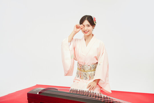 Smiling woman in pink kimono with traditional zither