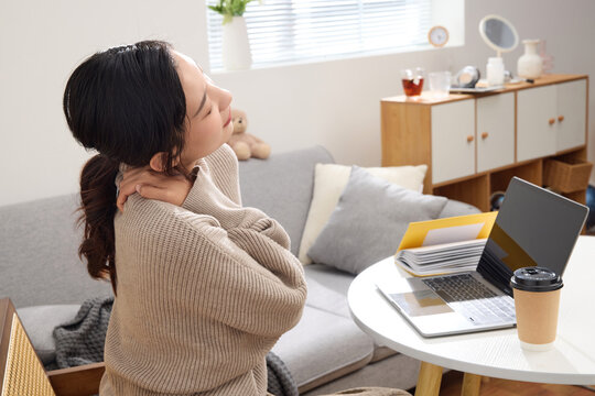 Young woman relieving neck pain during work break at home