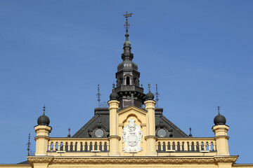 Obraz premium Ornate yellow building roofline with central tower, decorative balustrade, and imperial crest.