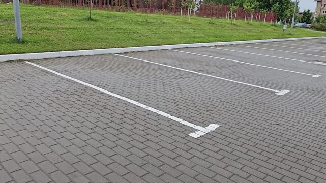 Empty parking lot in afternoon near residential area with clearly marked spaces and green grass around