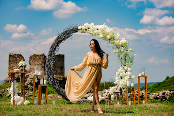 Naklejka premium Elegant bride woman under wedding arch. Romantic wedding arch outdoor scene. Bride under floral wedding decor. Luxury wedding arch with flowers. Beauty bride ceremony concept.
