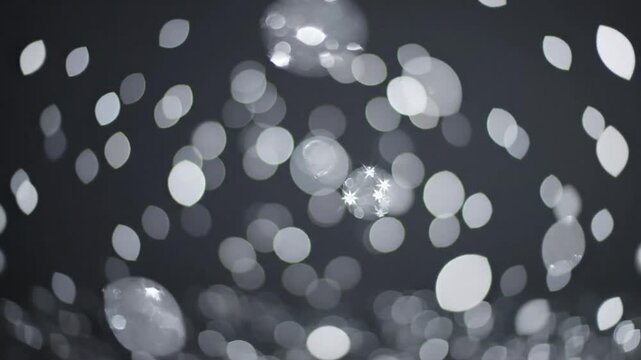 Abstract shimmering bokeh background of blurry shiny white lights against dark backdrop for tranquil visuals