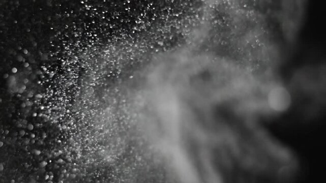 Abstract silver glitter particles floating in motion against black background