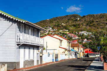Fototapeta premium View of colorful creole architecture and traditional wooden houses on a sunny street in the village of Les Anses d'Arlet, Martinique, Caribbean France