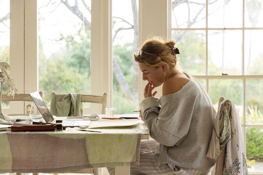 young woman artist doing watercolor drawing in her studio