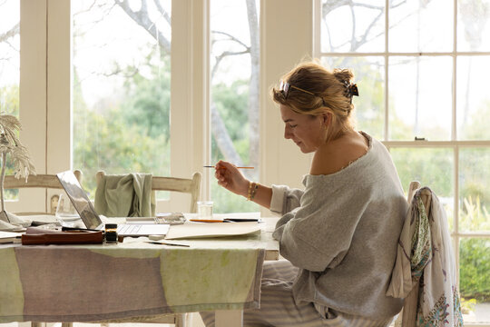 young woman artist doing watercolor drawing in her studio