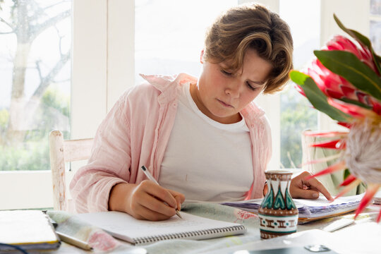 pre teen boy sitting at table doing homework