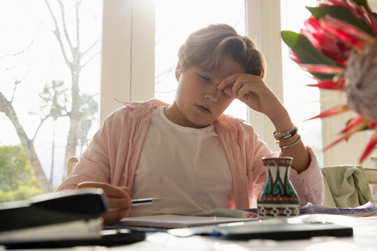 pre teen boy sitting at table doing homework