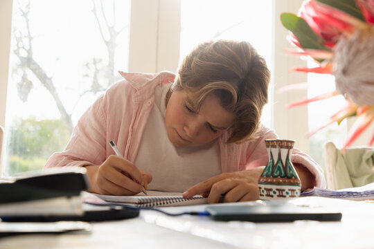 pre teen boy sitting at table doing homework