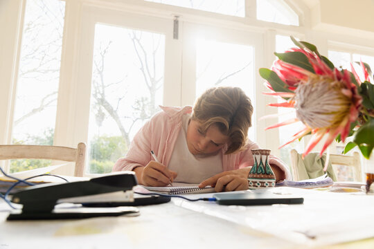 pre teen boy sitting at table doing homework