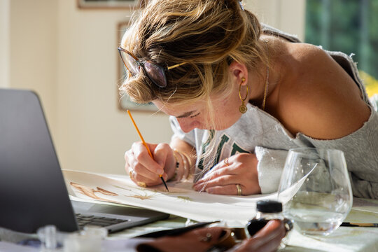 young woman artist working on a watercolor drawing in her studio