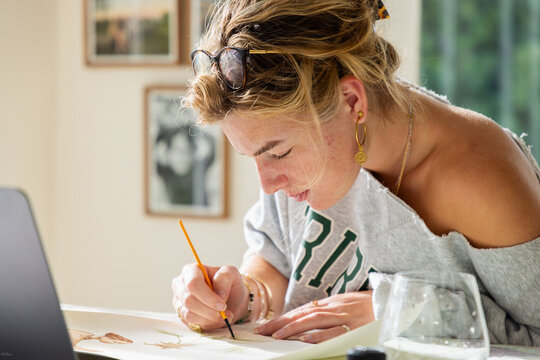 young woman artist working on a watercolor drawing in her studio