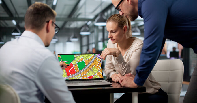 Urban Planner Team Studies Zoning Maps On Laptop