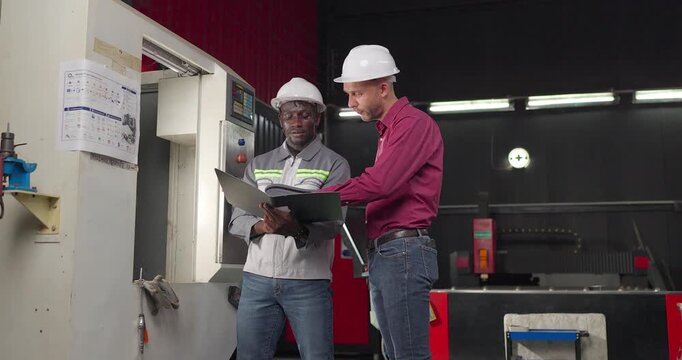 Sales engineer and client confirm a business agreement in an industrial workshop, shaking hands and reviewing contract documents for a custom manufacturing project.
