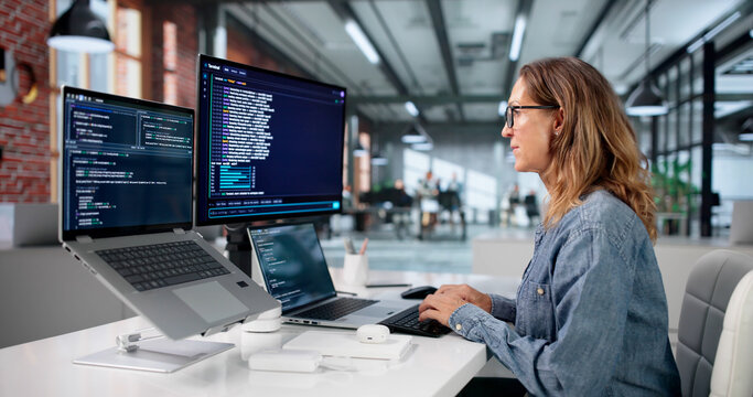 Mature Woman Coding Software On Laptop