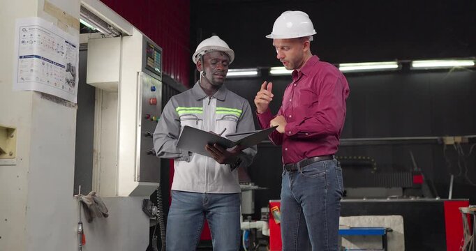 Sales engineer and client confirm a business agreement in an industrial workshop, shaking hands and reviewing contract documents for a custom manufacturing project.

