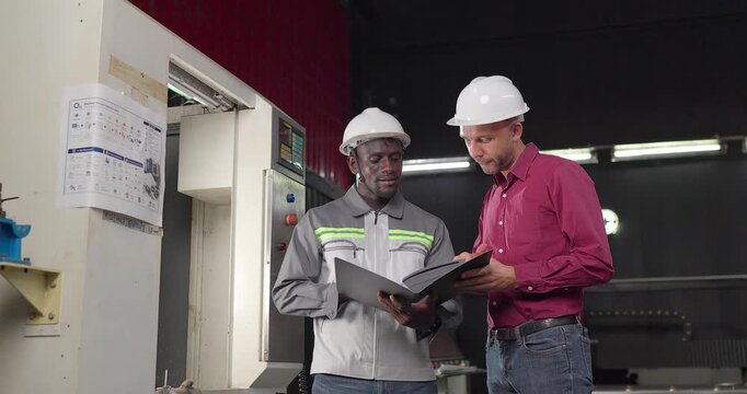 Sales engineer and client confirm a business agreement in an industrial workshop, shaking hands and reviewing contract documents for a custom manufacturing project.
