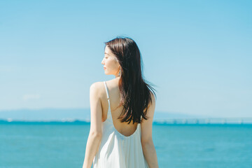 Obraz premium 青空背景の夏服の若いアジア人女性