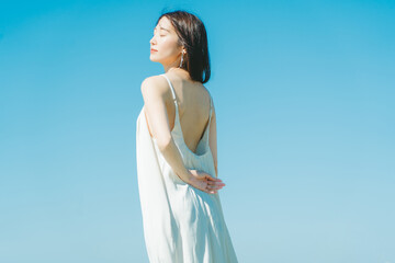 Obraz premium 青空背景の夏服の若いアジア人女性
