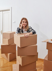 Fototapeta premium Happy woman leaning on stacked moving boxes