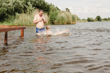 Fototapeta premium dynamic, relaxed shot boy jumping into natural lake. child is captured mid flight, creating sense excitement. image perfect family vacations, water safety, promoting active lifestyle among children