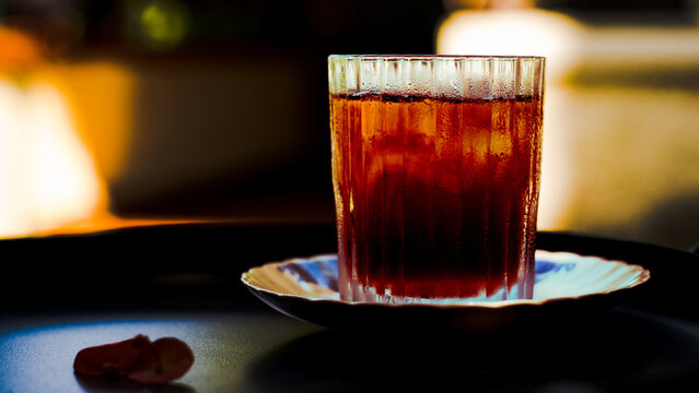 Cinematic close-up of iced Japanese-style coffee in a textured glass with soft warm background blur. Refreshing chilled coffee drink served in a cozy cafe setting with elegant lighting and shallow dep