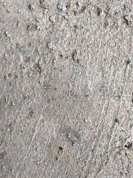 Texture of a rough grey cement plastered wall surface with uneven sand grain details