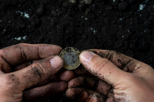 Dirty worker hands holding Hungarian two hundred forint coin symbolizing low wages