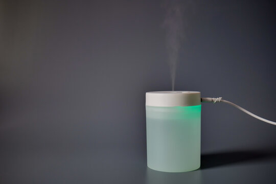 Compact portable air humidifier on a gray background, designed to improve indoor air quality and humidity levels