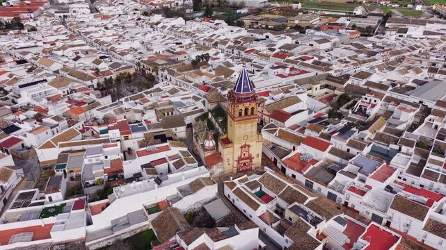 Church Nuestra Senora in El Coronil, Andalusia, Spain aerial view. Dynamic high angle drone footage of 15th-century parish church located in small Spanish city with white houses.