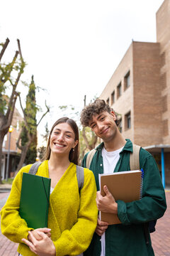 Two smiling students holding books on university campus