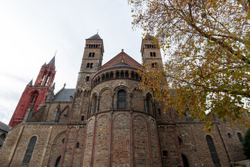 Fototapeta premium Low angle view of the ancient Basilica of Saint Servatius behind autumn trees in Maastricht