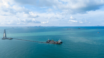 Obraz premium large construction barge equipped with excavators performing coastal land reclamation and rock armor installation at sea, representing maritime engineering, infrastructure development, and marine 