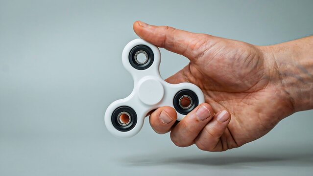 Hand holding fidget spinner isolated on gray background for stress relief concept