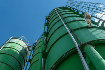 Green industrial cement silos at concrete batching plant symbolizing construction growth, infrastructure development and urban expansion © kalyanby