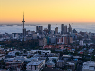 Obraz premium Auckland, New Zealand - The Sky Tower stands tall over the city skyline as fog rolls in from the Waitemata Harbour at sunrise.