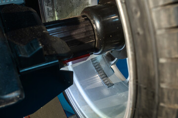 Obraz premium Wheel balancing weights attached to the inner side of a silver alloy rim in a car service workshop. Automotive maintenance service and tire repair concept focusing on car wheel parts