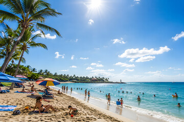 Obraz premium People enjoying a sunny tropical beach with golden sand and crystal clear blue water under a bright summer sky today