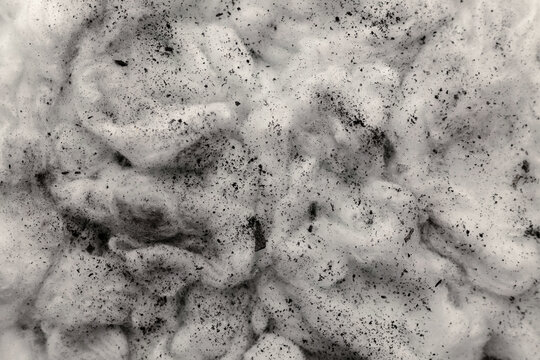 Black charcoal dust scattered on white cotton textured surface, pollution and environmental issue