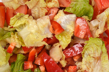 A detailed close up background view of a fresh mixed vegetable salad with lettuce leaves and chopped tomatoes © nahhan