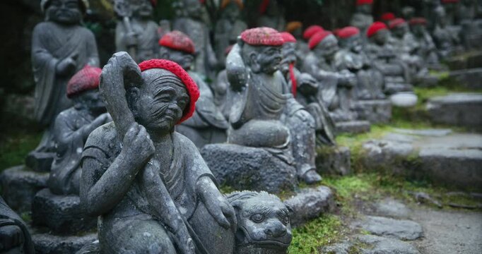 Row of Stone Rakan Statues with Red Knit Caps at Japanese Temple - Low, Closeup shot