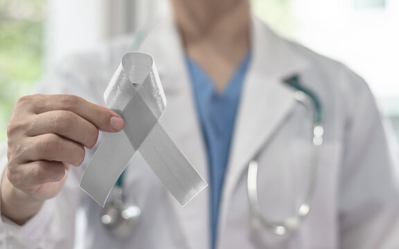 Silver color ribbon awareness on doctor's hand support, symbolic bow color for Parkinson's disease, Brain cancer, Schizophrenia, Sciatic Pain and Brain disorder or disability illness