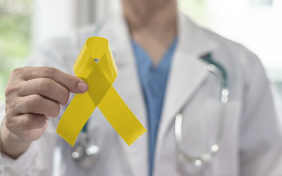 Yellow awareness ribbon for Sarcoma Bone cancer, Adenosarcoma, Bladder cancer, Liver disease, Spina Bifida Awareness Month and suicide prevention in doctor's hand