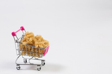 Uncooked pasta in a shopping cart on a white background © AI-Valentin