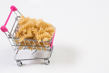 Uncooked pasta in a shopping cart on a white background © AI-Valentin